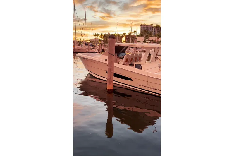 Slide: The Image of 2020 Regal 38 SAV boat docked at sunset with serene water reflections. - 28