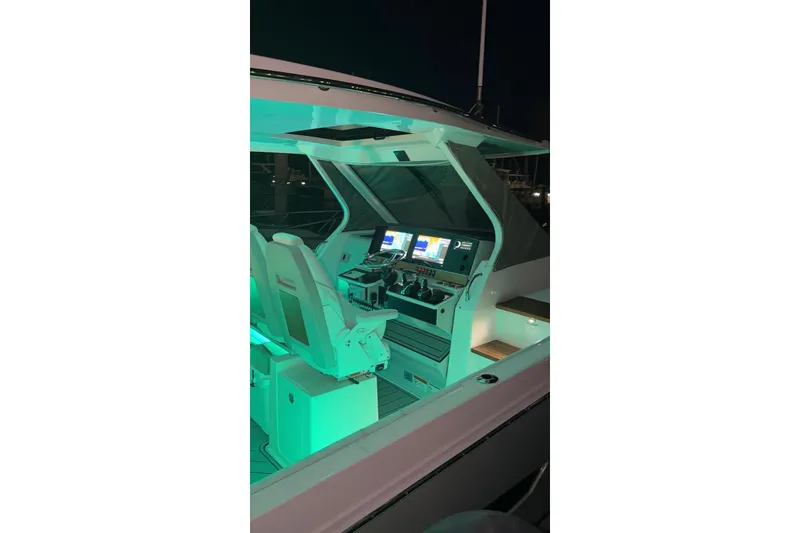 Slide: The Image of 2020 Regal 38 SAV boat cockpit with illuminated controls and dual screens at night. - 53
