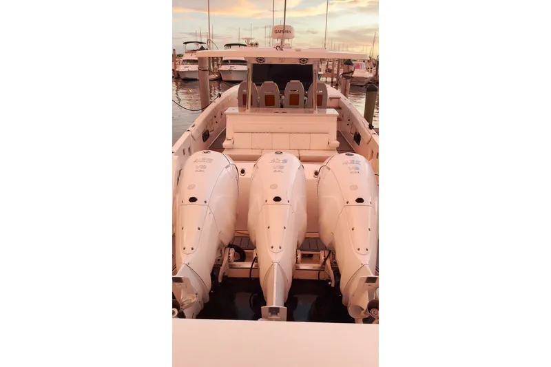 Slide: The Image of 2020 Regal 38 SAV boat with triple outboard engines docked at sunset. - 26