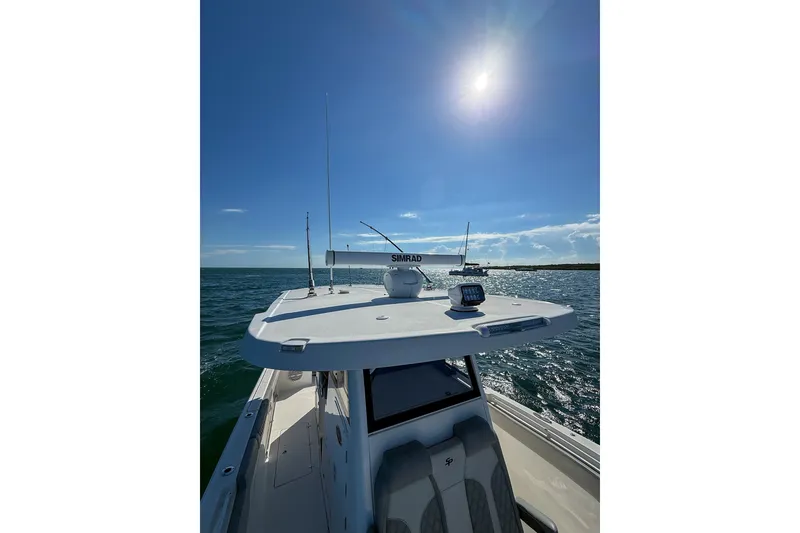 Slide: The Image of 2023 Sea Pro 320 DLX Offshore boat cruising under a bright sun on open water. - 16