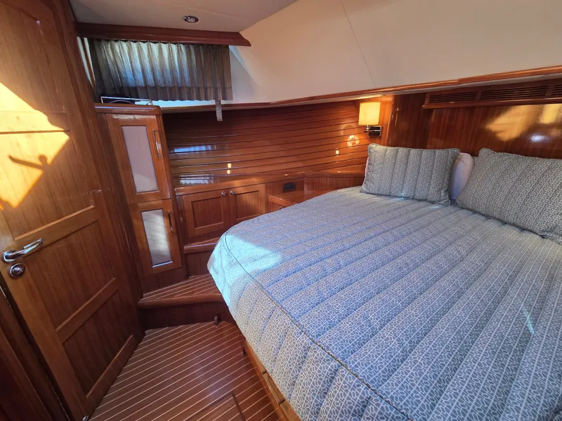 Slide: The Image of The cabin of a 2010 Grand Banks SX with a large bed and wooden walls. - 26