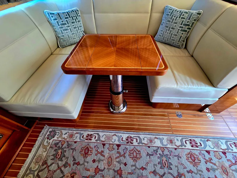 Slide: The Image of Interior of a 2010 Grand Banks SX with elegant seating area and wooden table on a wood floor. - 22