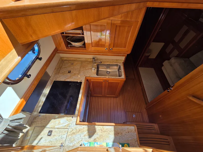 Slide: The Image of The galley of a 2010 Grand Banks SX with wooden cabinets, sink, and stove. - 34