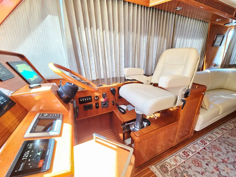 Slide: The Image of Interior of a 2010 Grand Banks SX with steering wheel, captain's chair, and wood finish. - 19
