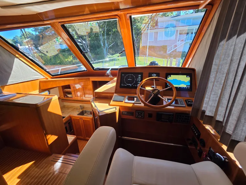 Slide: The Image of Interior of a 2010 Grand Banks SX with wood paneling, helm station, and large windows. - 16