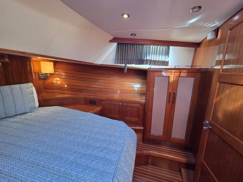 Slide: The Image of The 2010 Grand Banks SX cabin features a cozy bed, wooden walls, and a wardrobe. - 27