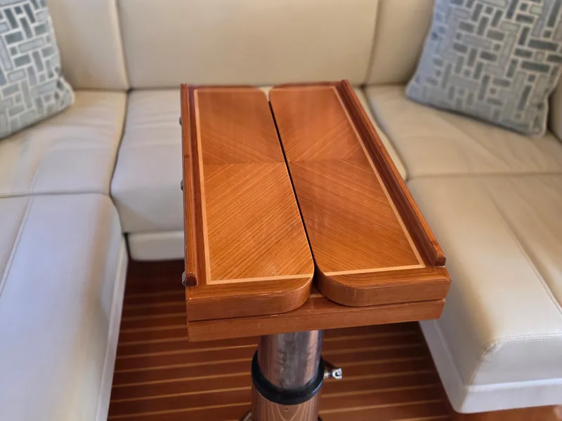 Slide: The Image of A sleek wooden table in a luxurious boat cabin with beige leather sofas. - 23