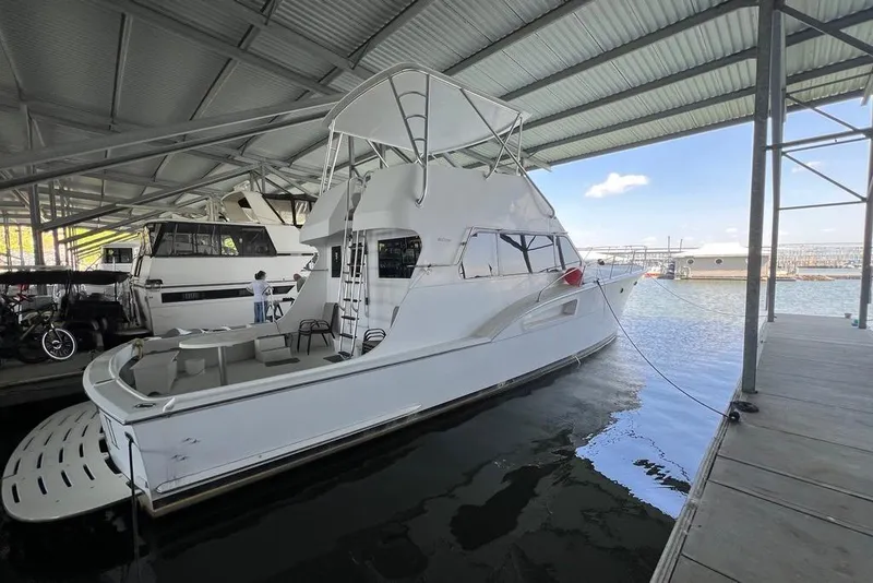 Slide: The Image of 1976 Hatteras 53 Convertible yacht docked under a covered marina. - 9