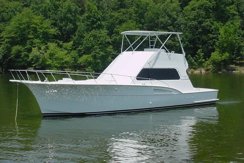 Slide: The Image of 1976 Hatteras 53 Convertible yacht on calm water, surrounded by lush greenery. - 3