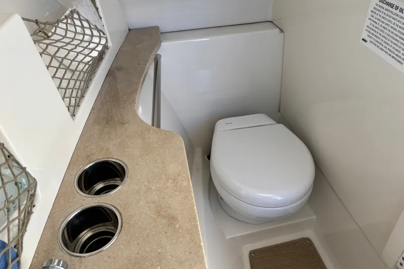 Slide: The Image of 2018 Sailfish 245 DC boat interior with compact marine toilet and storage area. - 16