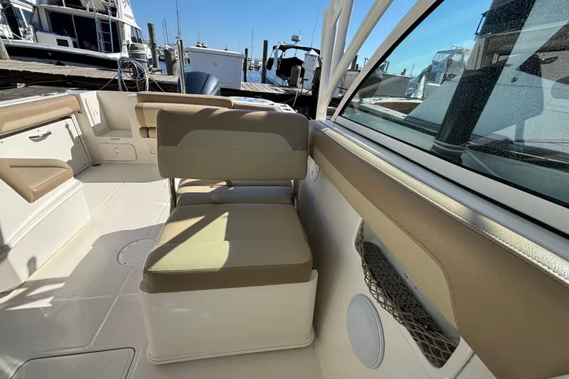 Slide: The Image of 2018 Sailfish 245 DC boat interior with beige seating and docked boats in background. - 19