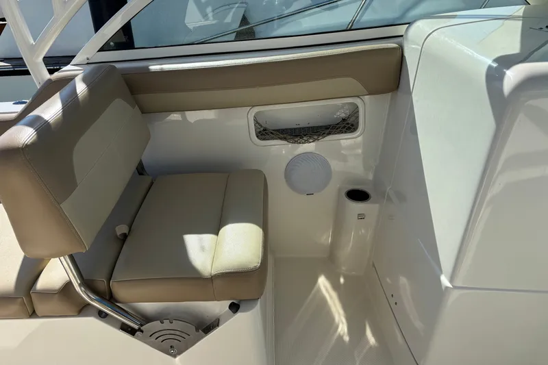 Slide: The Image of Interior seating of a 2018 Sailfish 245 DC boat, featuring beige cushions and storage compartments. - 14