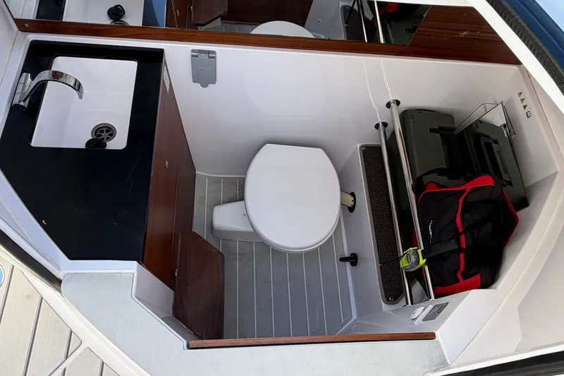 Slide: The Image of 2023 Axopar 28 T-Top boat interior with sink, toilet, and storage area. - 15