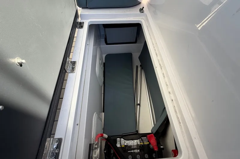 Slide: The Image of Storage compartment in 2023 Axopar 28 T-Top boat, featuring battery and seating area. - 26