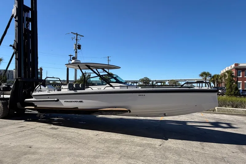 Slide: The Image of 2023 Axopar 28 T-Top boat on forklift, outdoor setting, clear blue sky. - 3