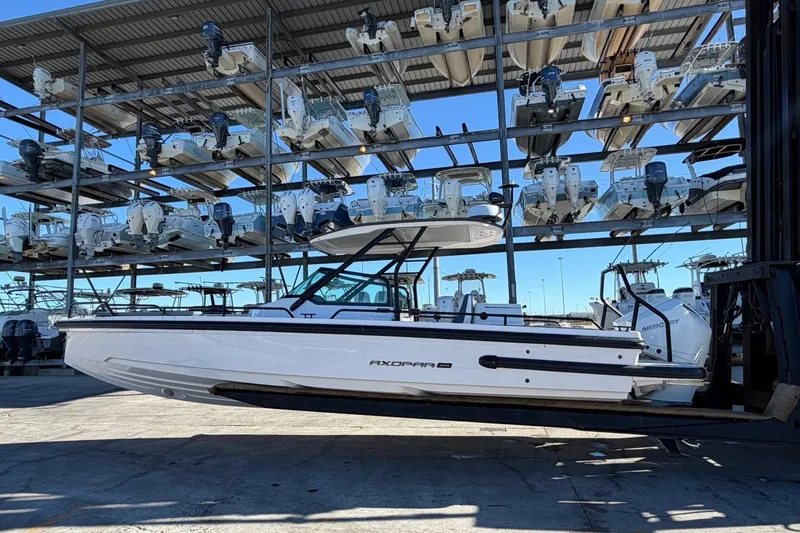 Slide: The Image of 2023 Axopar 28 T-Top boat in storage facility, surrounded by stacked boats. - 5