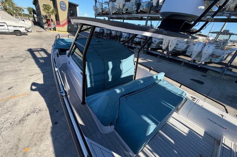 Slide: The Image of 2023 Axopar 28 T-Top boat with blue covers, docked at a marina. - 33
