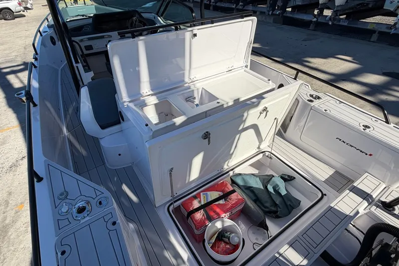Slide: The Image of 2023 Axopar 28 T-Top boat with open storage compartments and visible gear. - 32