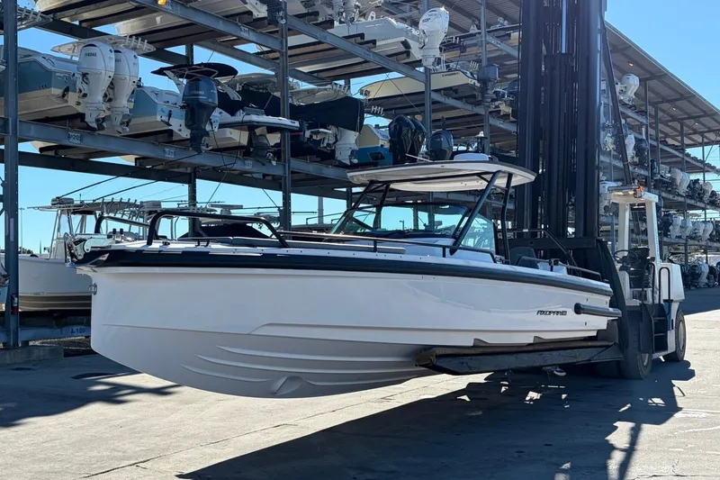 Slide: The Image of 2023 Axopar 28 T-Top boat on forklift at marina storage facility. - 1