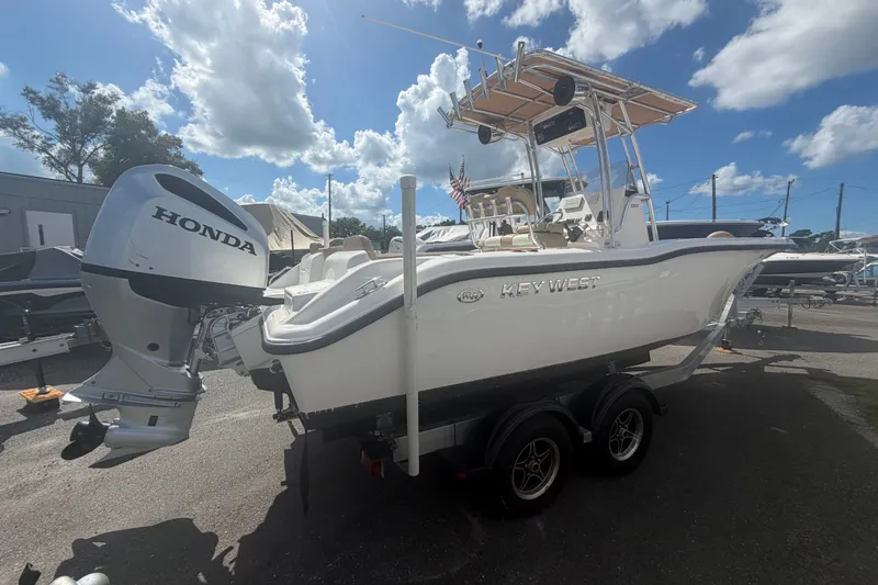 The Image of 2019 Key West 239 FS boat with Honda outboard motor, parked on a trailer under a sunny sky. - 0