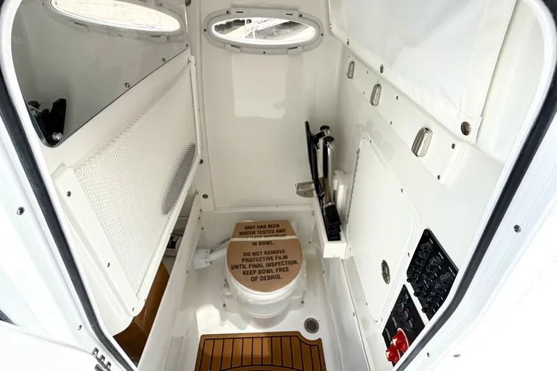 Slide: The Image of Interior of 2027 Sea Hunt Ultra 275SE boat featuring a compact marine toilet. - 27