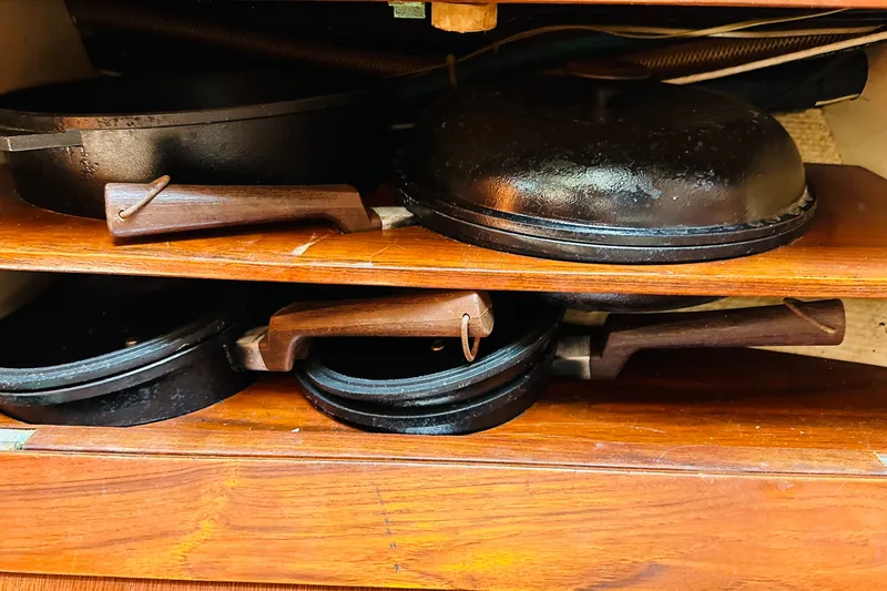 Slide: The Image of Cast iron pans with wooden handles stored on wooden shelves in a Cape George 36 Cutter. - 22
