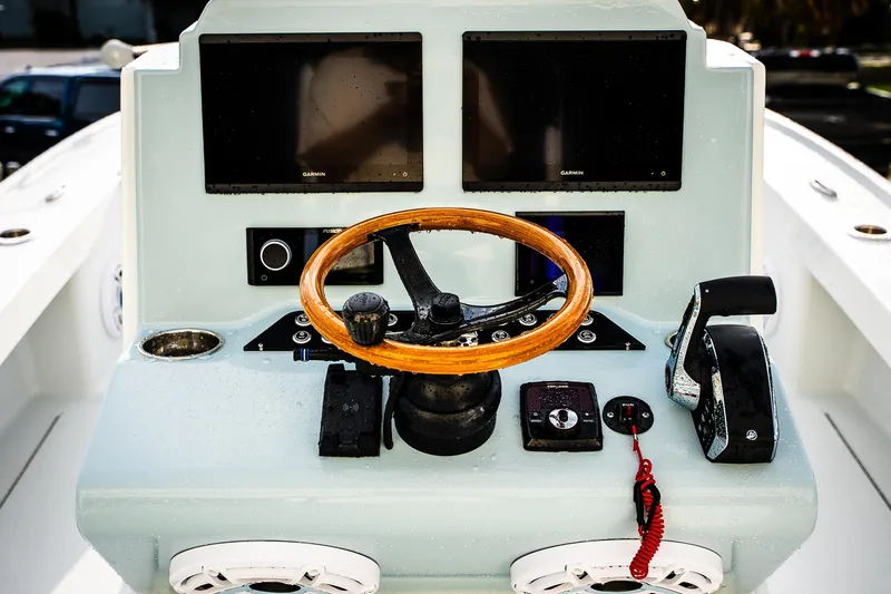 Slide: The Image of Steering console of 2026 Broadwater Boatworks 25 Bay Cat with dual screens and wooden wheel. - 26