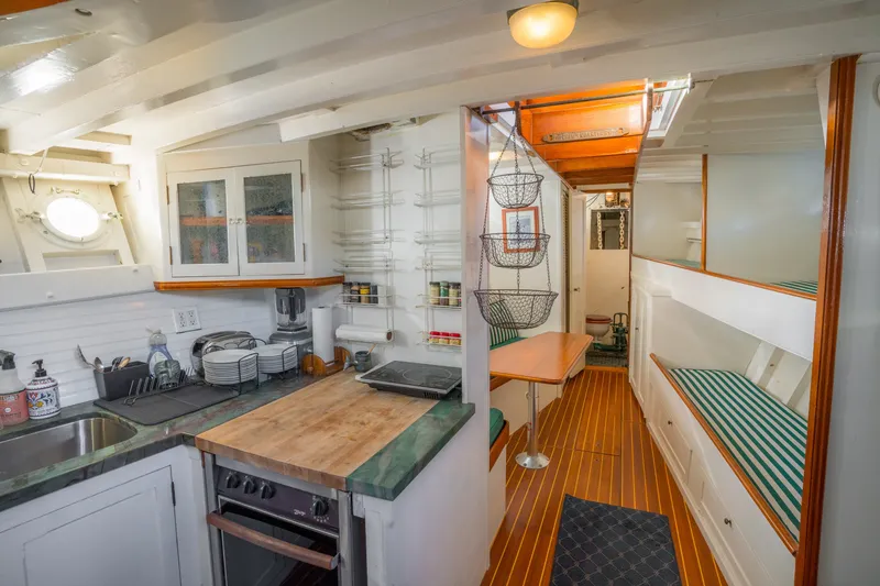 Slide: The Image of 1922 Blanchard Shipyard Custom boat interior with kitchen, dining area, and striped seating. - 3
