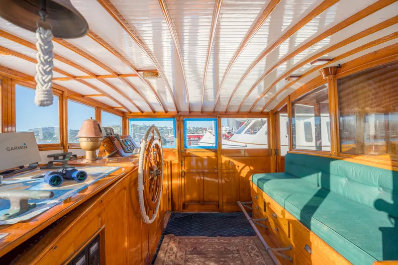 Slide: The Image of 1922 Blanchard Shipyard Custom boat interior with wooden helm, green seating, and nautical decor. - 24
