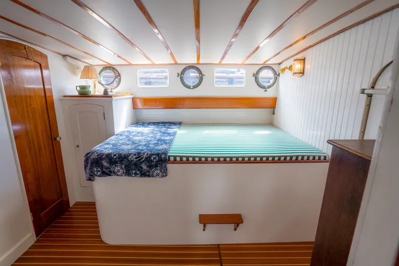 Slide: The Image of Cozy 1922 Blanchard Shipyard custom boat cabin with bed, portholes, and wooden accents. - 52