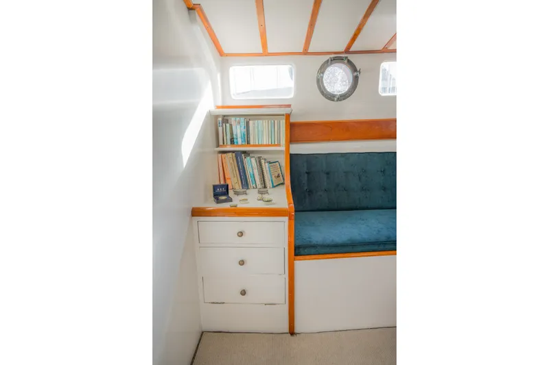 Slide: The Image of Cozy 1922 Blanchard Shipyard cabin with bookshelf, porthole, and cushioned seating. - 34