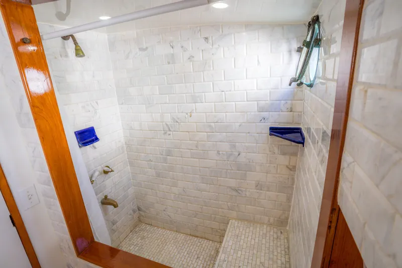 Slide: The Image of Luxurious shower with white tiles and blue accents on a 1922 Blanchard Shipyard Custom model. - 59