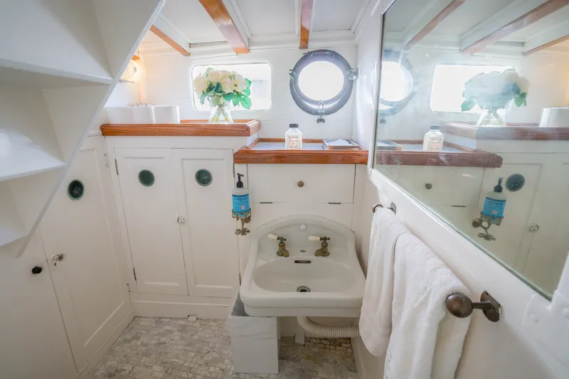 Slide: The Image of Vintage 1922 Blanchard Shipyard bathroom with porthole, white cabinetry, and floral decor. - 69