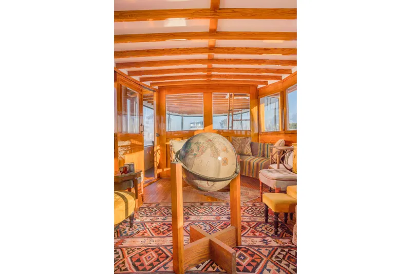Slide: The Image of Luxurious 1922 Blanchard Shipyard custom interior with globe, wooden beams, and patterned rug. - 9