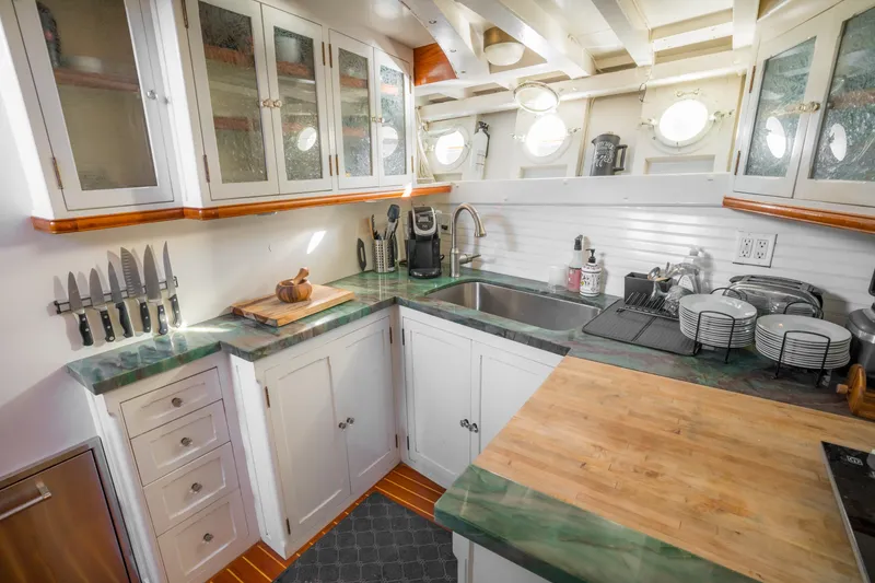 Slide: The Image of 1922 Blanchard Shipyard custom kitchen with green countertops, wooden accents, and nautical portholes. - 45