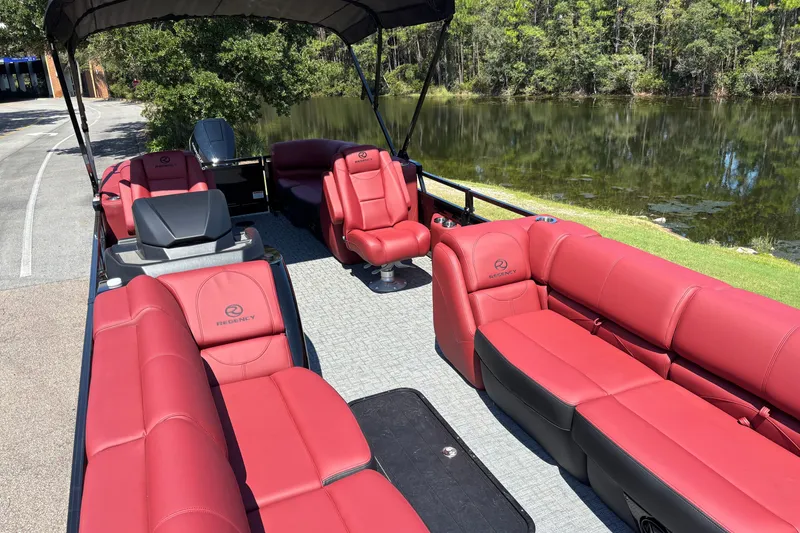 Slide: The Image of Luxurious 2027 Regency R250DL3 pontoon boat with red seating, docked by a serene lake. - 13