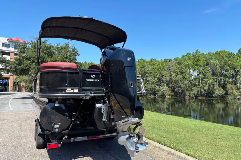 Slide: The Image of 2027 Regency R250DL3 boat with outboard motor, parked near a scenic lake. - 5