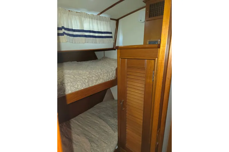 Slide: The Image of Bunk beds in the 2001 Grand Banks 43 Eastbay HX cabin, featuring wooden cabinetry. - 24