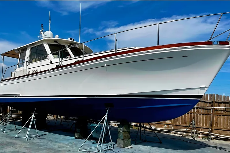 Slide: The Image of 2001 Grand Banks 43 Eastbay HX yacht on stands, blue hull, white deck, clear sky background. - 2