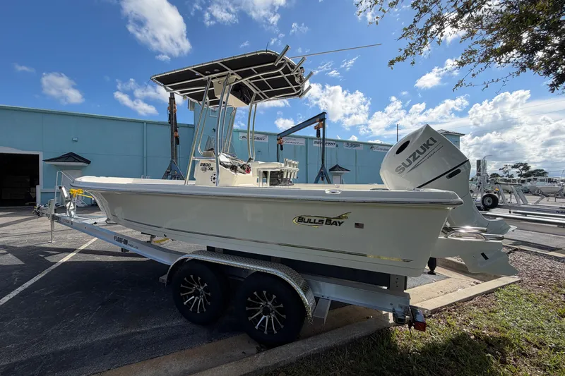 Slide: The Image of 2027 Bulls Bay 2200 XS boat on trailer, featuring Suzuki outboard motor, parked outdoors. - 3