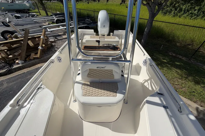 Slide: The Image of 2027 Bulls Bay 2200 XS boat interior with seating and console, parked outdoors. - 13