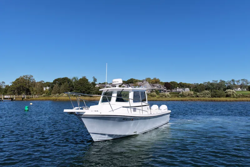 The Image of A 2024 Steiger Craft 255 Miami boat cruising on calm waters with a wooded shoreline. - 1