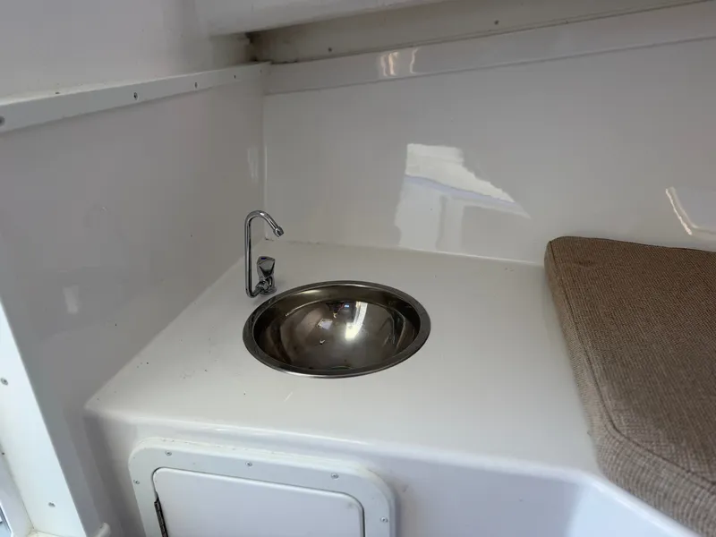 Slide: The Image of A compact wash area with a round stainless steel sink and faucet next to a cushioned seat. - 18