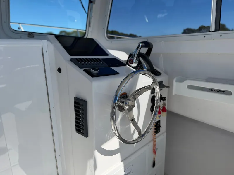Slide: The Image of The image shows the helm of a 2024 Steiger Craft 255 Miami with a shiny steering wheel. - 14