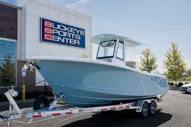 Slide: The Image of 2027 Sea Hunt Ultra 265SE in front of a sports center. - 2