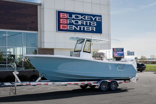 Slide: The Image of A Sea Hunt Ultra 265SE boat on a trailer in front of a sports center. - 1