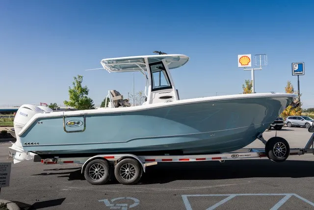 Slide: The Image of A 2027 Sea Hunt Ultra 265SE boat on a trailer, featuring a blue hull and white top. - 6