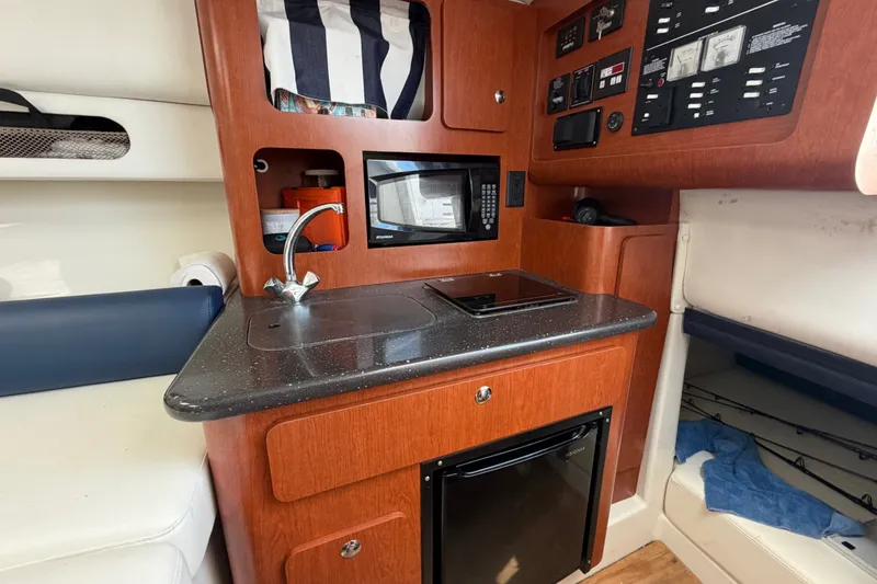 Slide: The Image of 2008 Pro-Line 32 Express boat interior with kitchenette, featuring sink, microwave, and control panel. - 31
