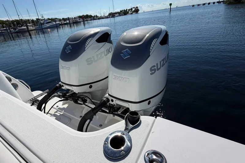 Slide: The Image of Twin Suzuki 300 outboard engines on a 2008 Pro-Line 32 Express boat, docked by the water. - 8