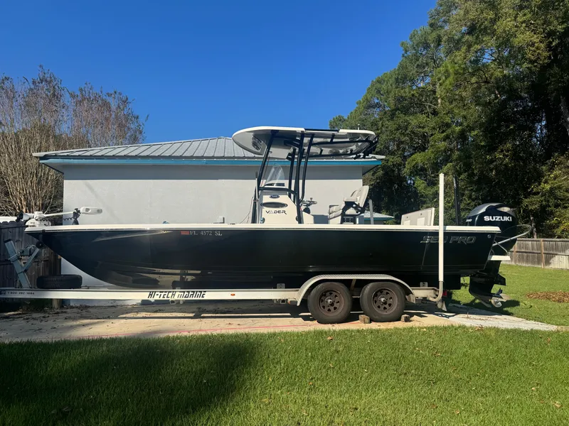 Slide: The Image of Sea Pro 248 Bay 2020 op een trailer, met Suzuki buitenboordmotor, geparkeerd voor een gebouw. - 3